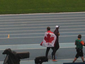 Derek Drouin wraps himself in the the Canadian flag after securing the bronze medal in the high jump. Photo: Chan Fan.