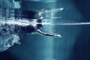 professional swimmer crawl underwater isolated blue background