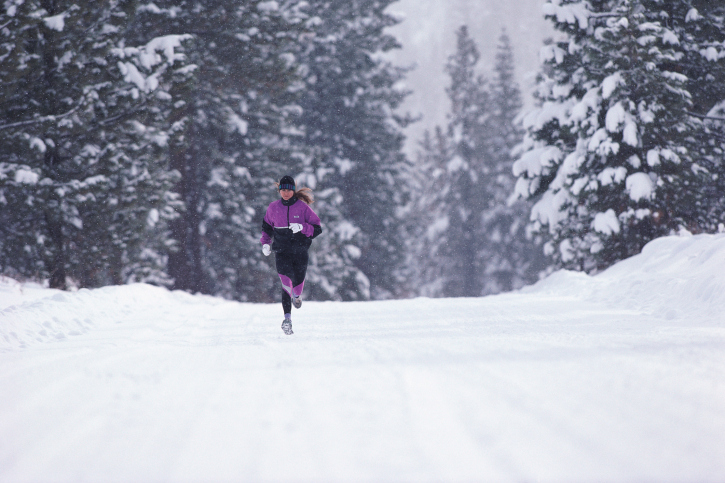 Woman jogging along road in winter