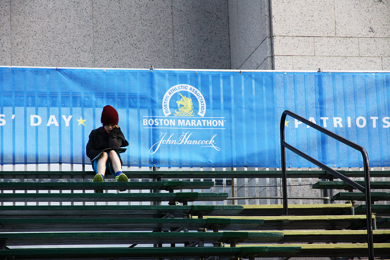 A boy reads in the grandstand before the 2015 Boston Marathon.