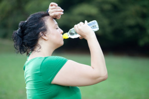 Sweaty overweight woman drinking water after a long run
