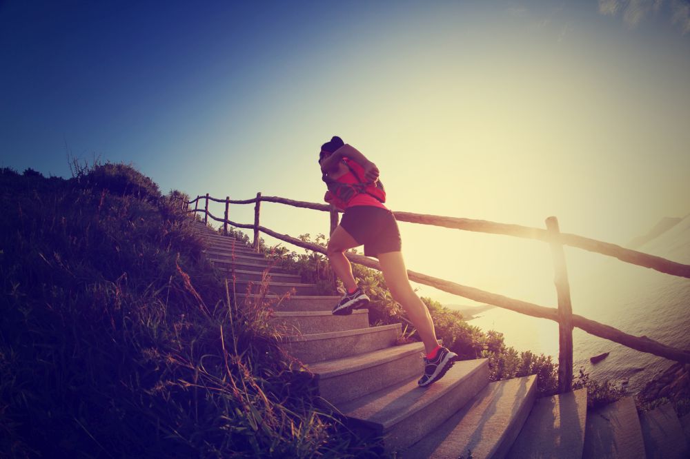young fitness woman runner running up on mountain stairs