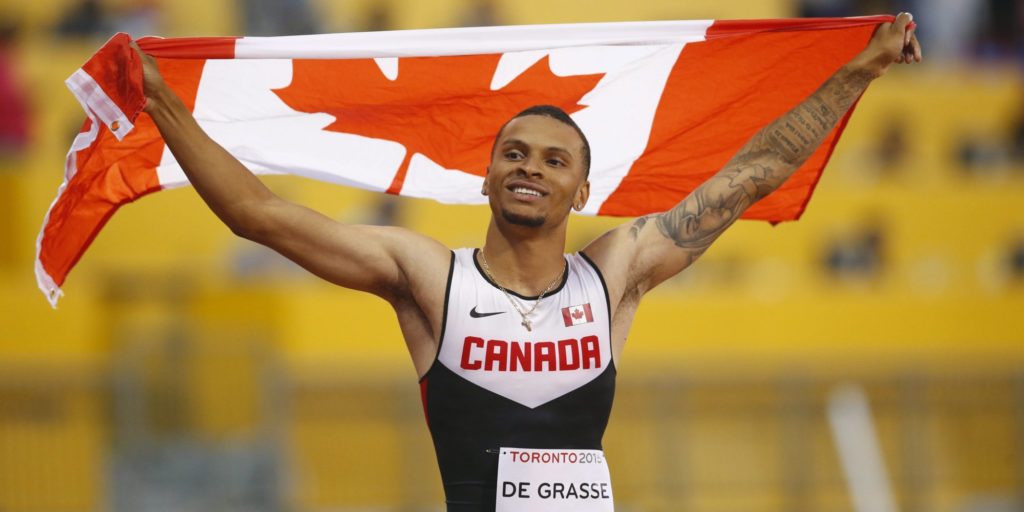 Andre De Grasse, of Canada, holds a flag after he wins the gold medal in the men's 100m final during the athletics competition at the 2015 Pan Am Games in Toronto on Wednesday, July 22, 2015. THE CANADIAN PRESS/Mark Blinch