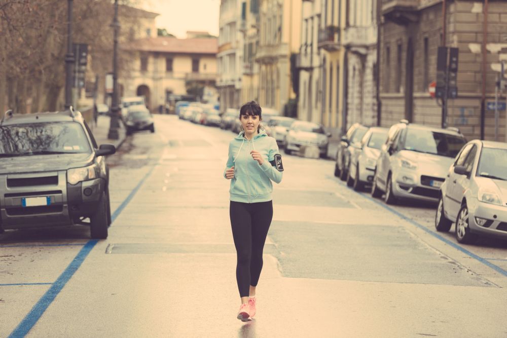 Beautiful young woman jogging alone in the city
