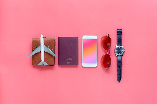 Flat lay image of accessory clothing man or women to plan travel in holiday background concept.Mobile phone & passport with many item in vacation season.Table top view several object on pink paper.