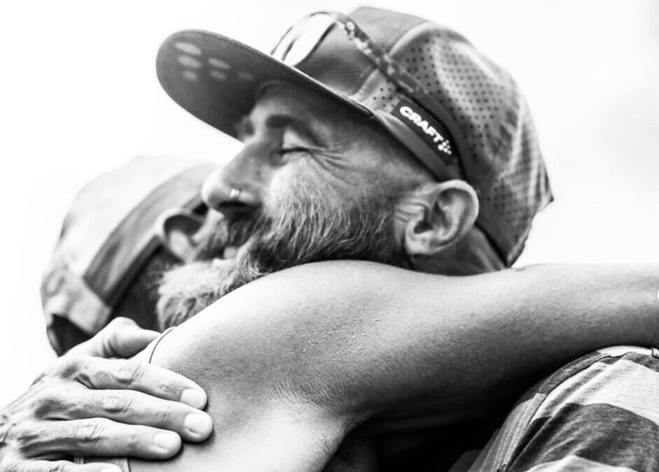 Tommy Rivs with beard hugging someone at Western States