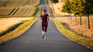 woman running on a road by fields