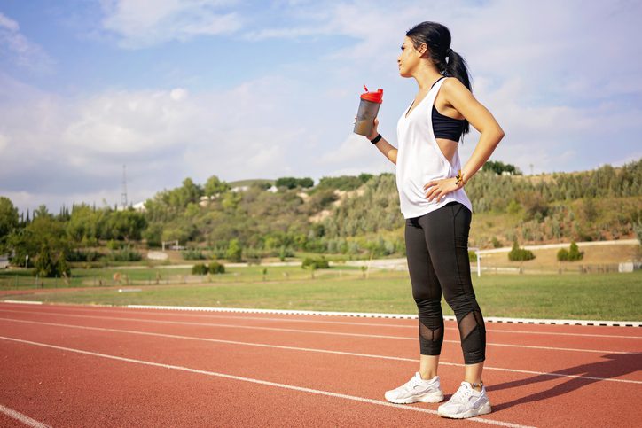 woman runner drinking water on track