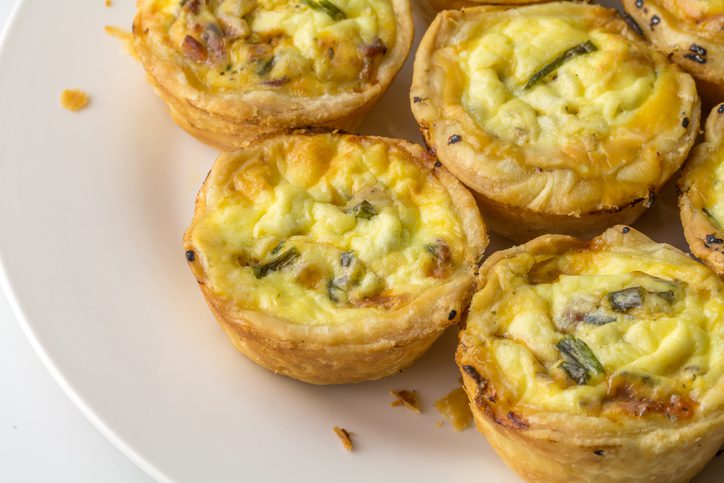 Plate with mini quiche with bacon and herbs - mini savoury pies on white with copy space